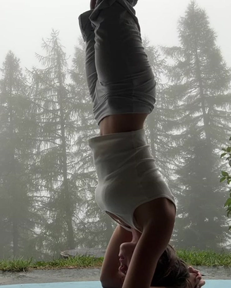 Milana doing a headstand on her yoga mat in a misty Swiss forest